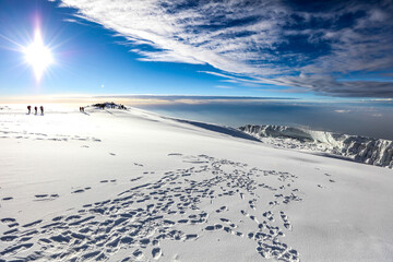 Clouds and blue sky above the snow covered summint of Mount Kilimanjaro