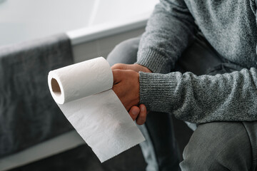 man with a paper roll in his hand sitting in the toilet