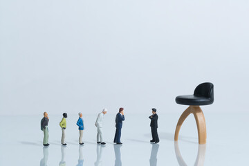 Applicants for a job stand in a row in front of the boss, large office chair in the background, miniature figures scene in the working world, white background, copy space - obrazy, fototapety, plakaty