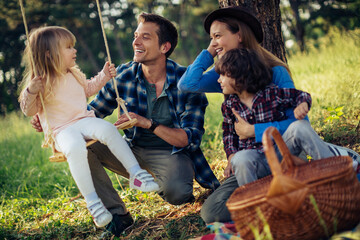 Fototapeta premium Happy young family having a picnic in the park during a sunny day