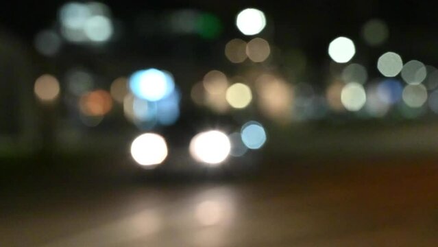 Defocused headlights from car traffic by night on the city street