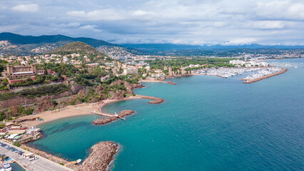 Aerial view of Mount Turnei, located on the French Riviera. Photography was shot from a drone at a higher altitude from above the water wit the beautiful marina and beach in the view. - obrazy, fototapety, plakaty