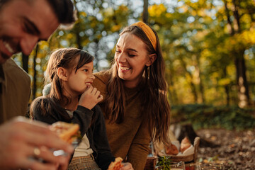 Mother, father and daughter eating fruit during forest picnic