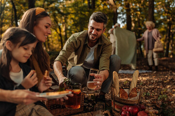 Mother, father and their daughter having a picnic while grandparents set up