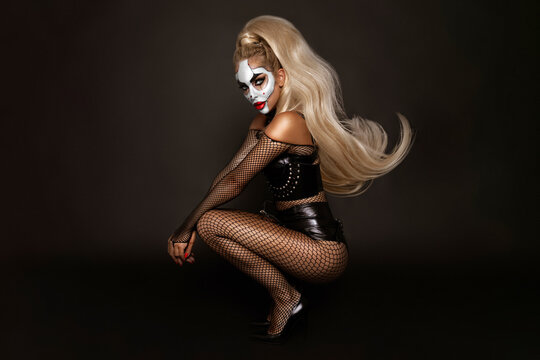Sexy woman in a Halloween makeup and latex costume on black background. Halloween makeup and costume concept.