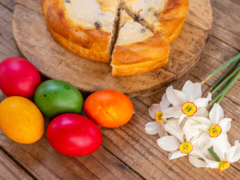 traditional romanian easter dish cozonac and pasca or sweetbread and cheese pie like on wooden table and colored easter eggs and flowers aside