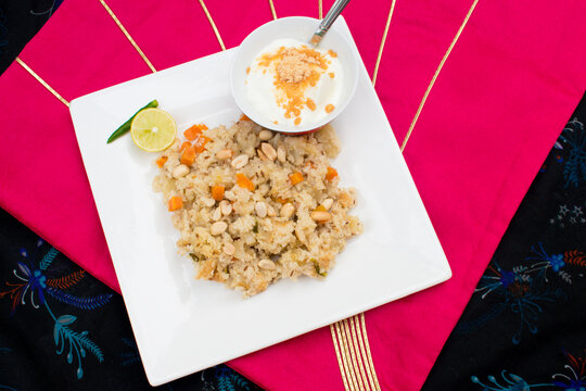Indian Vrat thali. Fasting or Upwas food in white plate containing samak or sama rice pulav or pulao and curd with jaggery or gur . fasting food platter.