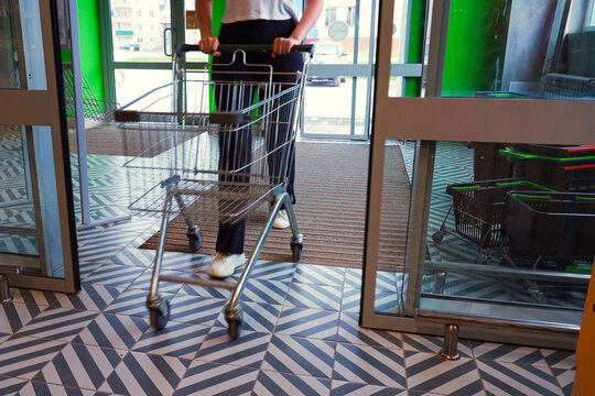 A woman with a grocery cart enters a store