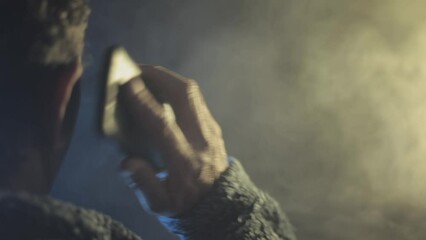 Cinematic shot of an unrecognizable gangster in a dark gothic environment talking to someone on his phone. HD footage.