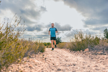Man running on a rocky path in nature under cloudy skies