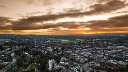 the sun sets over the city and mountains behind it as seen from the air