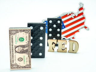 dollar banknote on dominoes with fed in between dominoes piece and us flag on white background, financial crisis concept