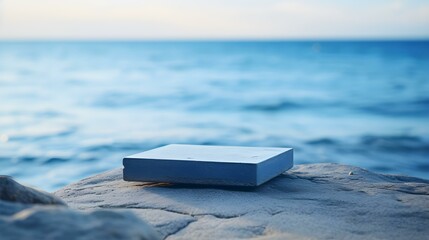Square Stone Podium in blue Colors in front of a blurred Seascape. Luxury Backdrop for Product Presentation