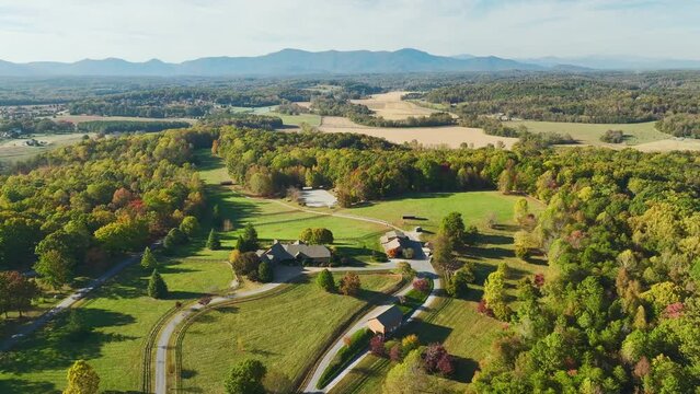 Aerial view of North Carolina countryside. Large expensive farmhouse surrounded with farm fields and dense woods close to Appalachian mountains