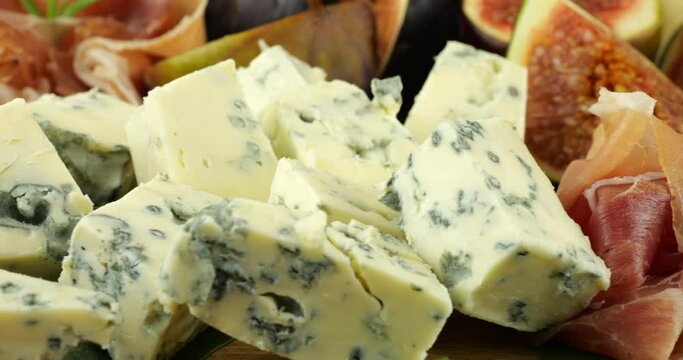 Figs, jamon, spinach leaves and blue cheeses on a wooden board. Snacks set.