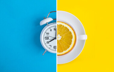 Collage of white alarm clock and white cup with fresh halved orange on the colored  background. Top...