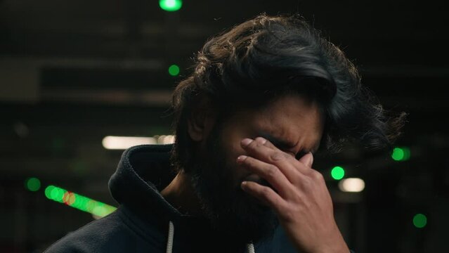 Pensive thoughtful Arabian male thinking feeling bad take off glasses feel eyes discomfort eye pain Indian man guy ache blurry vision problem eyestrain sight trouble outdoors underground parking lot