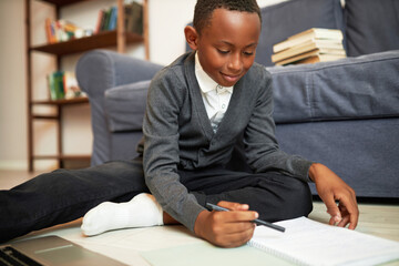 Homeschooling, remote education, distant learning. Side view of smart black boy in school uniform...