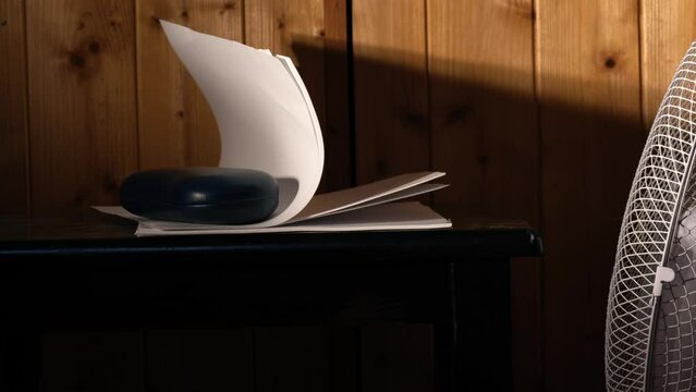 Office desk fan blowing notepad paper