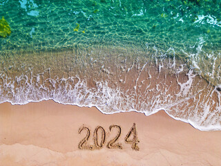 2024 year written on sandy beach sea at sunny day - obrazy, fototapety, plakaty