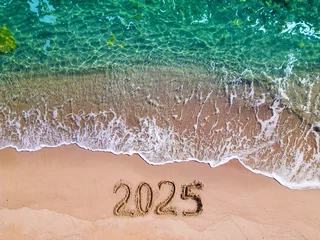 Fotobehang 2025 year written on sandy beach sea at sunny day © sandsun