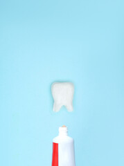Closeup of a toothpaste and tooth model on blurred blue background. Means to care for the oral cavity.