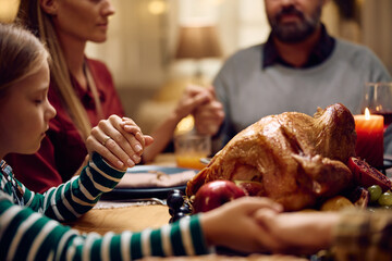 Close up of family holding hands and praying before meal on Thanksgiving.