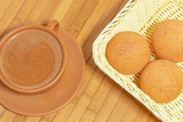 A cup of chocolate and three colombian buñuelos on a wooden table. Typical Colombian food. Breakfast.