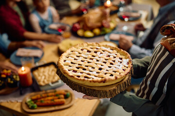 Close up of woman serving Thanksgiving pie to her family at dining table.