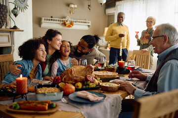 Cheerful multiracial family has fun while gathering for Thanksgiving at home. - obrazy, fototapety, plakaty