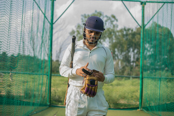 cricket player wearing hand gloves, ready to do practice in nets.