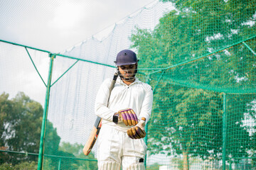 Cricket Player wearing gloves to do practice in cricket nets.