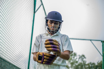 Low angle shot of Cricket player wearing hand gloves to do practice in cricket nets.