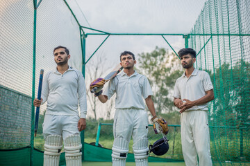 Cricket players standing a giving team poses in cricket nets in practice time
