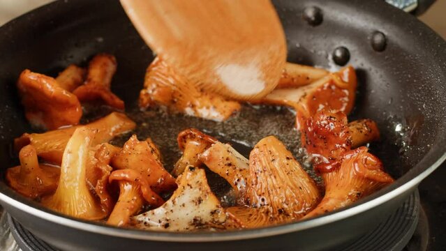 Fried chanterelle mushrooms with onion and parsley in a frying pan and the ingredients cooking i9n restaurant, autumn menu in cafe.