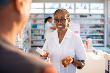 Senior pharmacist offering advice to a customer at the drugstore