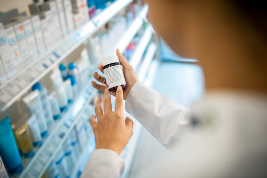 Close up of a female pharmacist reading medication labels at the drugstore