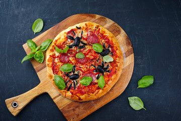 Traditional Italian Halloween spider pizza with salami, chili and olives designed as spiders served...