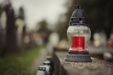 Close up of Votive candles lantern on the grave in Slovak Catholic cemetery during day. Autumn scene. All Hallows eve. Memorial to the deceased. Solemnity of All Saints. 1st November, All Saints' Day