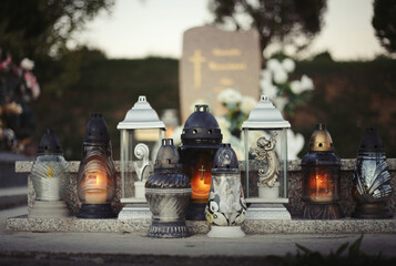 Close up of Votive candles lantern on the grave in Slovak Catholic cemetery during day. Autumn scene. All Hallows eve. Memorial to the deceased. Solemnity of All Saints. 1st November, All Saints' Day