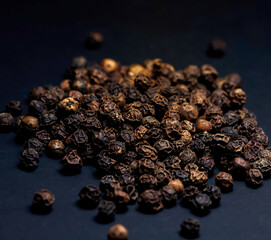 Black peppercorns on a black background.