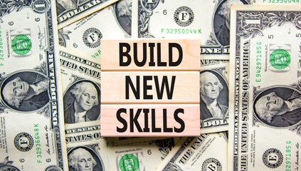 Build new skills symbol. Concept word Build new skills on beautiful wooden block. Dollar bills....