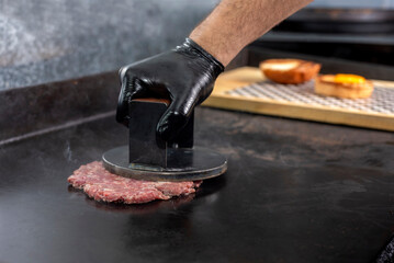 manufacturing and cooking process of homemade meat burgers on an iron plate with chedar cheese and pan bread and wrapping - obrazy, fototapety, plakaty