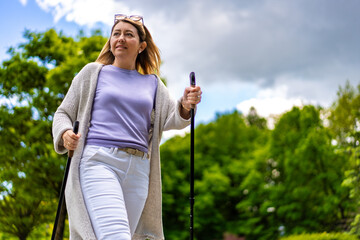 Nordic walking - woman exercising in city park
