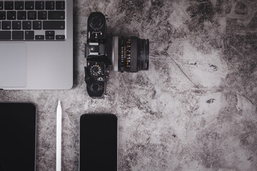 Top view of grunge cement table with computer laptop, camera, smartphone, tablet and digital pen in concept of digital content creator, photographer and freelancer. - obrazy, fototapety, plakaty