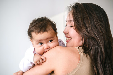 Young asian mother holding little baby girl and smiling