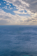 Obraz premium Blue sea with blue sky with clouds, vertical seascape
