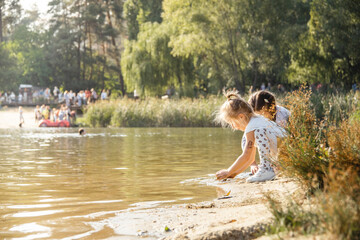 Fototapeta premium Cute little girl is having fun on the beach while playing with wet sand. Hot sunny summer day