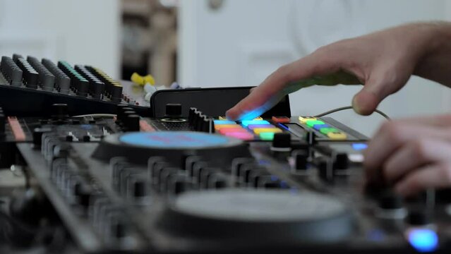 A man works on a mixer in a club. The sound engineer uses a music mixer. Mixer control of light and sound. Mixer setup. Music player to set up the scene close-up.