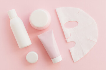 Set of cosmetic products for face care in white color on a pink background. Beauty. Self care. Moisturizing the skin of the face. Cream, face mask, serum, lip balm.